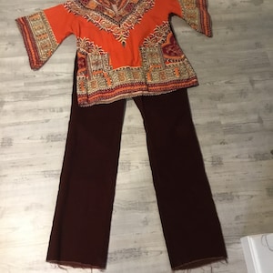 May include: A two-piece outfit featuring a bright orange top with a geometric pattern and brown bell-bottom pants.