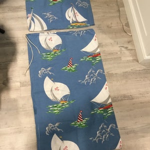 May include: Two pieces of blue fabric with a white sailboat pattern. The fabric has red and white buoys and white clouds. The fabric is for sewing projects.