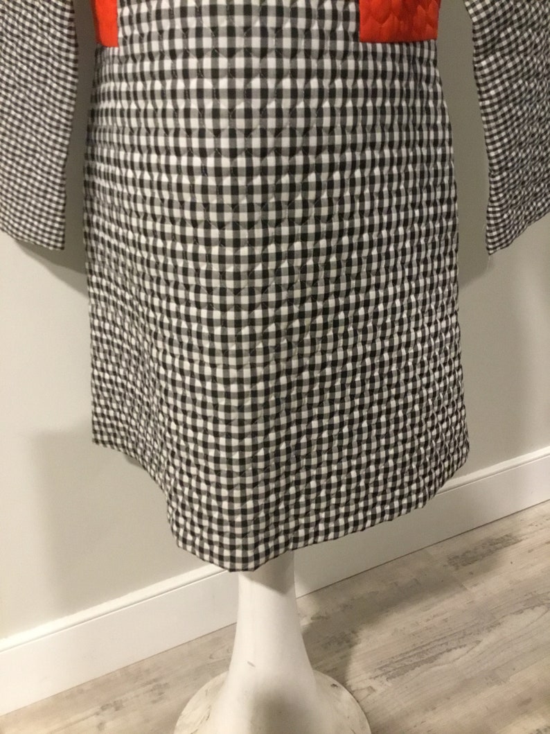 May include: A black and white gingham quilted dress with a red panel on the front.