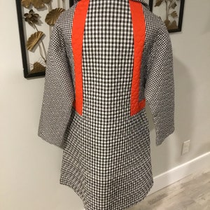 May include: A black and white gingham quilted coat with a bright orange accent down the back.