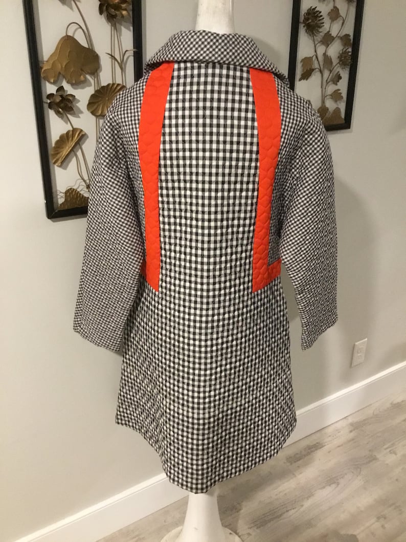 May include: A black and white gingham quilted coat with a bright orange accent down the back.
