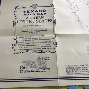May include: A vintage Texaco road map of the Western United States. The map features a blue and white color scheme with a scale of miles and a map explanation key. The map includes a universal road signal with hand gestures for left and right turns. The text on the map reads "Texaco Road Map Western United States" and "On this map is shown the new federal highway numbering authorized by the American Association of State Highway Officials, November, 1934."