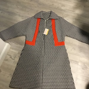 May include: A black and white gingham robe with orange trim. The robe has a zipper closure and a collar.