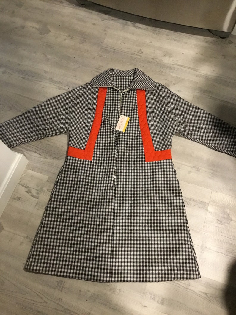 May include: A black and white gingham robe with orange trim. The robe has a zipper closure and a collar.