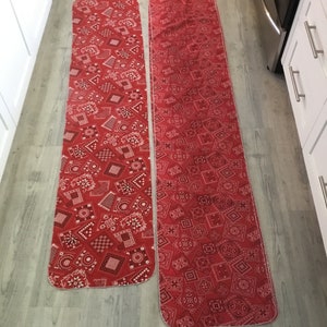 May include: Two red and white patterned runner rugs with a bandana print. The rugs are on a light wood floor.
