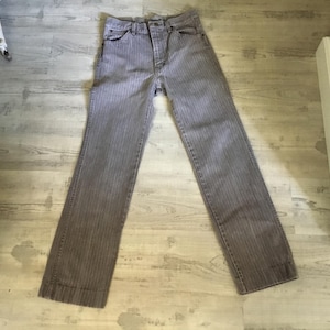 K&ouml;nnte beinhalten: Eine graue gestreifte Jeans mit Knopfleiste und G&uuml;rtelschlaufen.