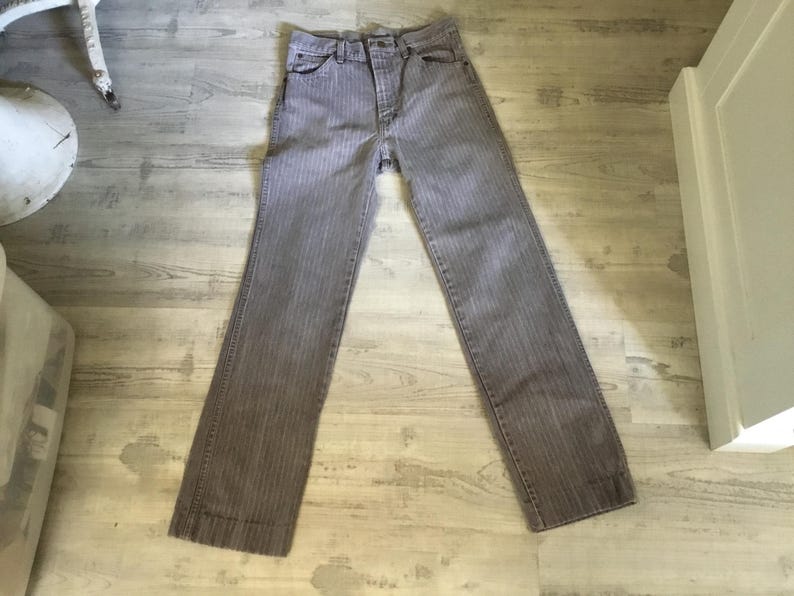 K&ouml;nnte beinhalten: Eine graue gestreifte Jeans mit Knopfleiste und G&uuml;rtelschlaufen.