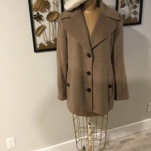 May include: A brown wool coat with a large collar and a button closure. The coat is on a mannequin with a white beret.