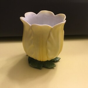 Peut inclure: Un vase en céramique jaune en forme de tulipe avec une base en feuille verte.