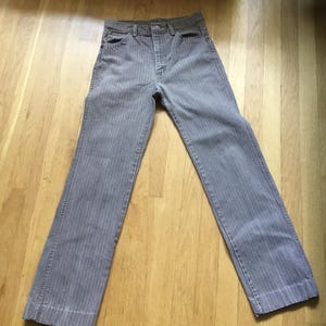 K&ouml;nnte beinhalten: Graue gestreifte Hose mit Knopfleiste.