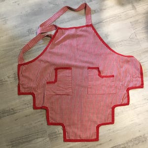 May include: Red and white checkered apron with red trim and two pockets.