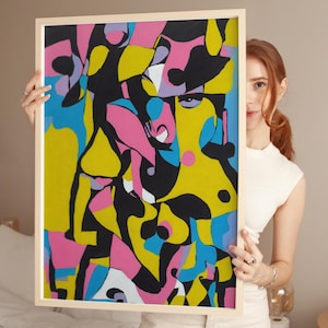 Op de afbeelding: Abstracte kunstprint in een houten lijst. De print heeft een kleurrijk ontwerp met roze, gele, blauwe en zwarte vormen.