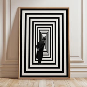Puede incluir: Impresión artística en blanco y negro enmarcada. Muestra a un hombre con abrigo y sombrero negros mirando una serie de rectángulos concéntricos en blanco y negro. La obra está en un marco de madera y se apoya en una pared blanca.