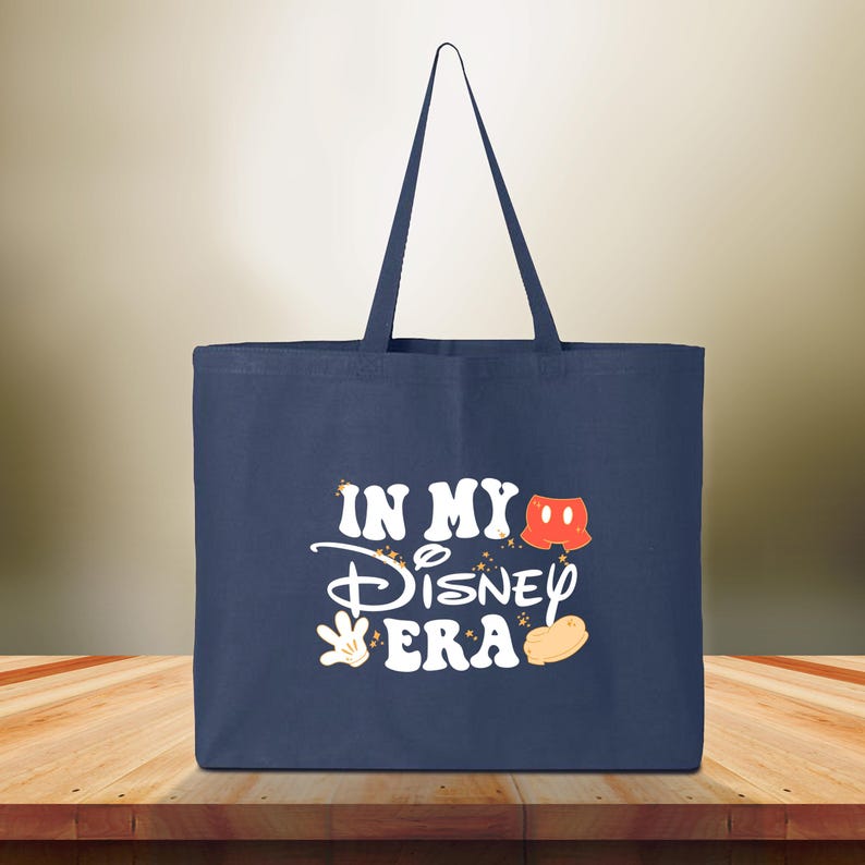 Pu&ograve; includere: Borsa tote blu navy con la scritta "IN MY Disney ERA" in bianco, con grafica a tema Mickey Mouse. La borsa ha una forma rettangolare e due manici.