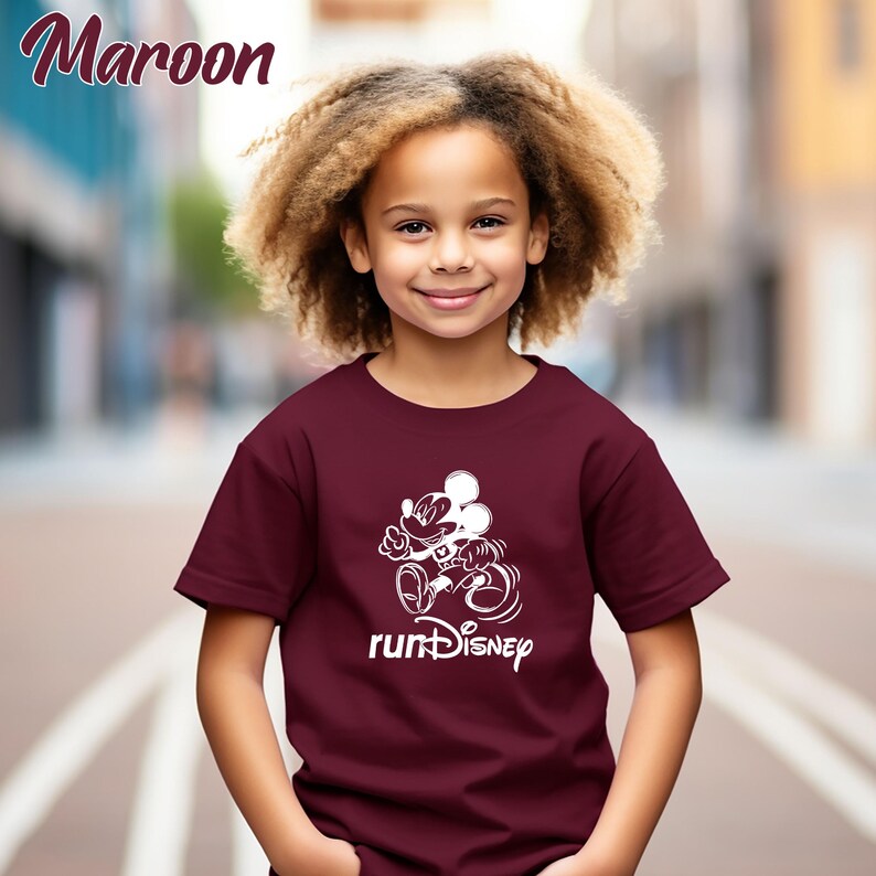 May include: Maroon t-shirt featuring a white graphic of Mickey Mouse running, with the text "runDisney" below. The shirt is short-sleeved and has a crew neck. The word "Maroon" is written in the upper left corner.