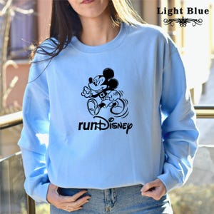 May include: Light blue sweatshirt featuring a black Mickey Mouse graphic running and the text "runDisney".