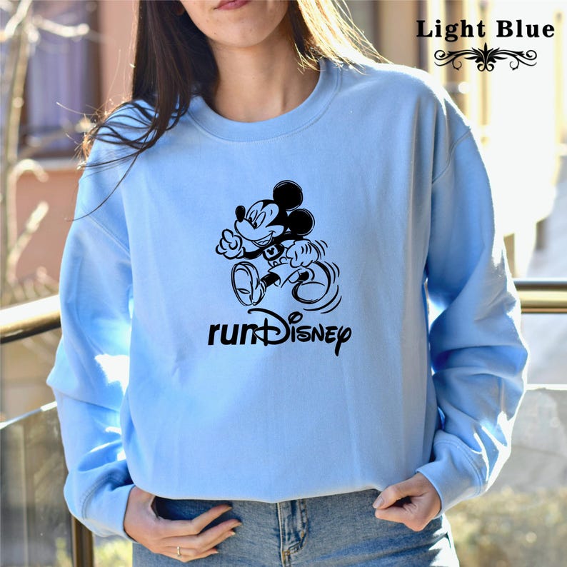 May include: Light blue sweatshirt featuring a black Mickey Mouse graphic running and the text "runDisney".
