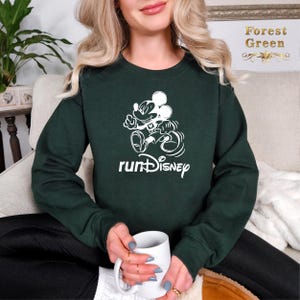 May include: A dark green sweatshirt with a white graphic of Mickey Mouse running and the text "runDisney".