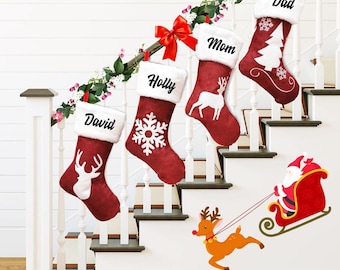 May include: Four red Christmas stockings with white faux fur cuffs hang on a staircase. Each stocking is personalized with a name and features a different holiday design, including a snowflake, a deer, and a Christmas tree. A decorative garland and a Santa and reindeer decal complete the festive scene.