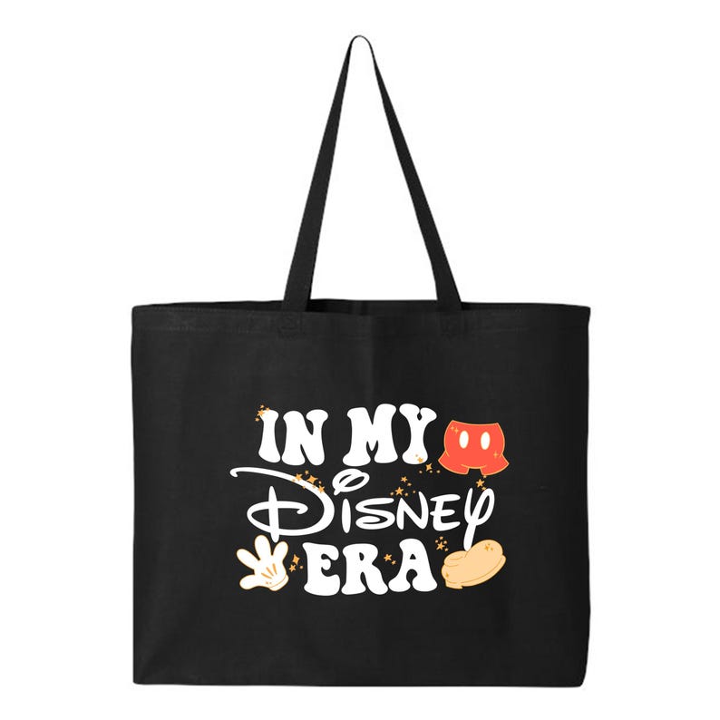 Pu&ograve; includere: Borsa tote nera con la scritta "IN MY Disney ERA" in bianco. Il design include i pantaloncini rossi, i guanti gialli e le scarpe di Topolino. La borsa ha lunghi manici neri.