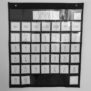 May include: A black and white calendar with a clear plastic cover. The calendar is for September 2019. Each day of the month is displayed in a separate square.