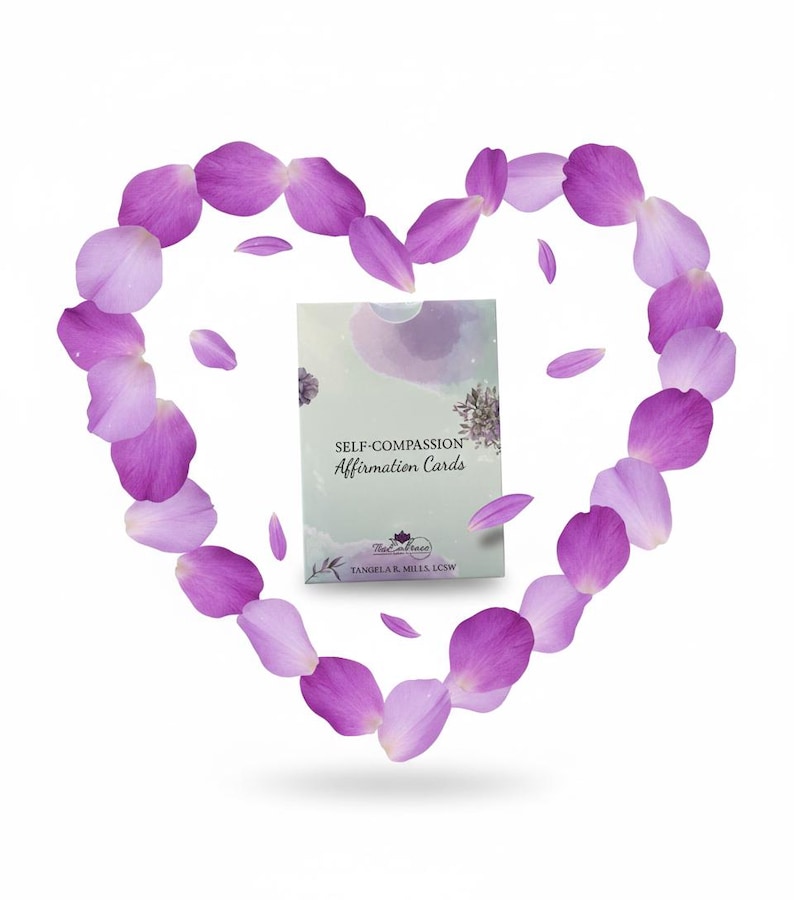 May include: A deck of "Self-Compassion Affirmation Cards" is centered within a heart shape made of purple flower petals. The card deck has a light green background with the text "Self-Compassion Affirmation Cards". The petals are various shades of purple.