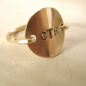 May include: A gold ring with a round, spinning charm that says "CTR" on it.