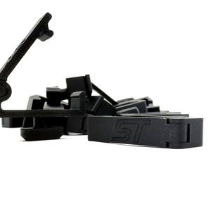 May include: A collection of black plastic clips and fasteners, some with the letters "ST" embossed on them. The objects are scattered against a white background, with a focus on the details of the shapes and textures.
