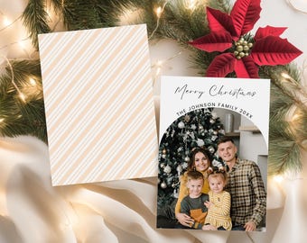 Peut inclure: Une carte de Noël avec une photo de famille et le texte "Merry Christmas". La carte présente une photo d'une famille devant un sapin de Noël. Le dos de la carte présente un motif à rayures diagonales beige et blanc.