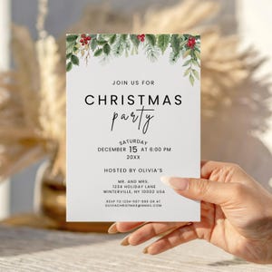 Könnte beinhalten: Eine weiße Weihnachtspartei-Einladung mit grünen und roten Aquarell-Botanikelementen. Die Einladung lautet "Join us for Christmas Party" mit Datum, Uhrzeit und Gastgeberdetails. Die Einladung wird von einer Person gehalten.