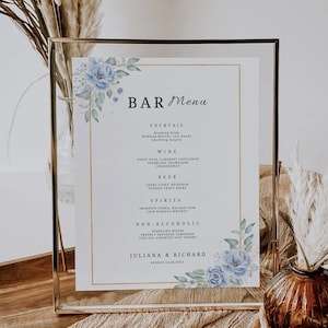May include: A clear glass frame holds a bar menu with a gold border and floral accents. The menu lists cocktails, wine, beer, spirits, and non-alcoholic drinks. The names Juliana & Richard and the date are at the bottom.