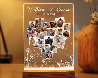 Könnte beinhalten: Eine personalisierte Fotoanzeige mit einer herzförmigen Collage von Bildern. Die transparente Acrylplatte wird von einem warmen Licht von der Holzbasis beleuchtet. Die Namen "William & Emma" und das Datum "05-02-2021" sind oben angezeigt.