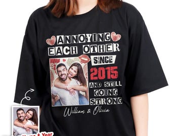 Puede incluir: Camiseta negra con el texto "ANNOYING EACH OTHER SINCE 2015 AND STILL GOING STRONG" y una foto de una pareja. La camiseta también presenta los nombres "William & Olivia" y una pequeña foto con el texto "Custom Name & Year Upload Photo".