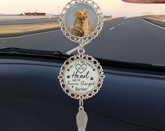 May include: A silver car charm featuring a photo of a golden retriever in a decorative frame. The charm has a second circular pendant with the text "You left paw prints on my heart and I'm forever changed, Barker."