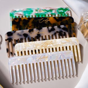 May include: A white ceramic mug with a black handle and the text "But First, Coffee" in a handwritten style. The mug is on a white surface. The mug is 10 cm tall.