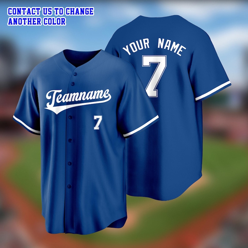 May include: Two blue baseball jerseys. One jersey has "Teamname" and the number "7" in white on the front. The other jersey has "Your Name" and the number "7" on the back. Both jerseys have white trim on the sleeves.