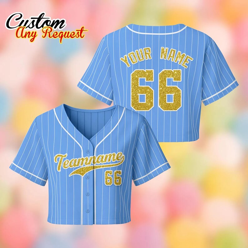 May include: Light blue baseball jersey with white pinstripes, featuring the text "Teamname" and the number "66" in gold glitter on the front. The back displays "Your Name" and "66" in gold glitter. The words "Custom Any Request" are in the top left corner.