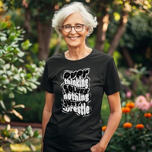 May include: A black t-shirt with white text that reads "Over thinking solves nothing just wrestle".