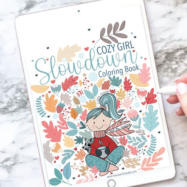 Op de afbeelding: Een digitale illustratie van een meisje met een kopje koffie en een klein dier dat in een cirkel van bladeren en harten zit. De tekst "Cozy Girl Slowdown Coloring Book" staat bovenaan de afbeelding.