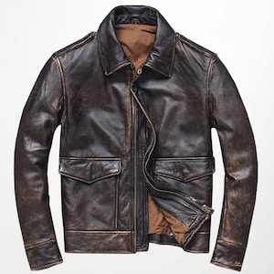 Könnte beinhalten: Eine braune Lederjacke im Used-Look mit klassischem Kragen, zwei Vordertaschen und Reißverschluss. Die Jacke hat einen Vintage-Look mit sichtbaren Gebrauchsspuren und einem braunen Innenfutter. Die Ärmel sind lang.