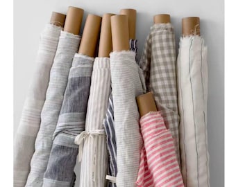 May include: A collection of fabric rolls in various patterns and colors. The fabrics include stripes, checks, and solid colors, with shades of white, gray, blue, and pink. The rolls are displayed against a white background.