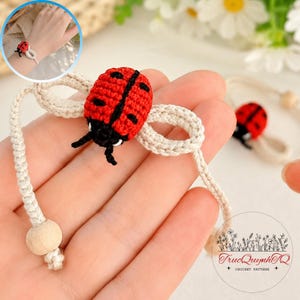 May include: A handmade crochet bracelet featuring a red and black ladybug motif centered on a beige cord. The ladybug has a textured red body with black spots and a black head. The bracelet includes beige crocheted loops and a light wooden bead.