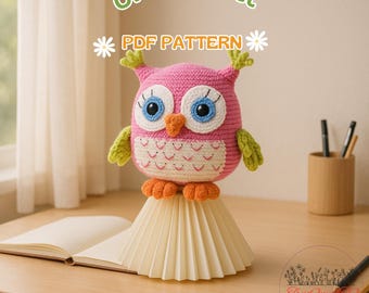 May include: A handmade pink crochet owl with blue eyes, orange beak, and green accents. The owl is perched on a cream-colored paper structure. The text "OWL Crochet PDF PATTERN" is displayed above the owl.