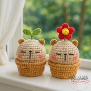 May include: Two crocheted plant-like figures with bear ears, blush cheeks, and closed eyes. One has a green sprout, the other a red and yellow flower. They sit in brown crocheted pots, creating a whimsical, handmade aesthetic.