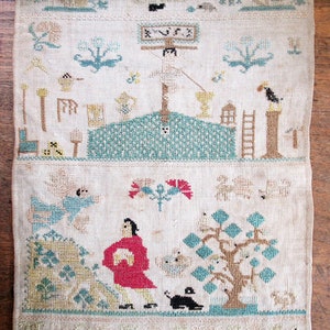 以下が含まれることがあります： 詳細なクロスステッチのデザインが施されたアンティーク刺繍テキスタイル。人物、木、建築要素など、さまざまなシーンが描かれており、すべてクリーム色の背景に青、緑、赤、茶色の落ち着いた色合いで表現されています。このテキスタイルは、リネンまたは同様の生地である可能性があります。