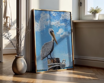 Könnte beinhalten: Gerahmtes Gemälde eines Pelikans auf einem Holzpfahl vor blauem Himmel mit weißen Wolken. Das Kunstwerk hat einen goldenen Rahmen und wird drinnen an eine Wand gelehnt.