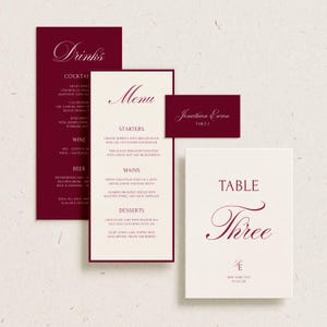 May include: A set of elegant wedding stationery in burgundy and cream. Includes a drinks menu, a dinner menu, a place card, and a table number card. The text is in a classic script font.