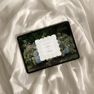 May include: A digital tablet displaying a wedding invitation with a white scalloped border over a background of blue and white hydrangeas. The text reads: You are cordially invited to the wedding of Lianna and Nathan, May 30, 2030, Sydney, Australia.