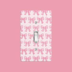 May include: A white light switch cover with a pink bow pattern. The switch is labeled "OFF".
