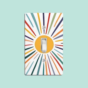 May include: A light switch cover with a colorful sunburst design. The sunburst is made up of thin lines in various colors, including red, orange, yellow, green, blue, and purple. The sunburst surrounds a yellow circle with a white light switch in the center. The light switch is labeled "OFF".